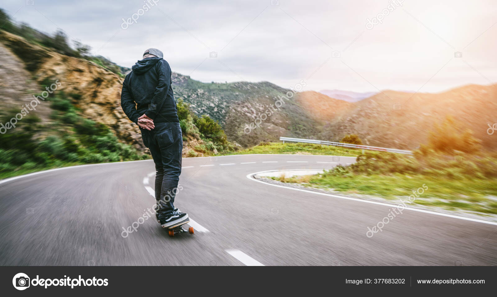 Back View Man Riding Skateboard Curvy Mountain Asphalt Road
