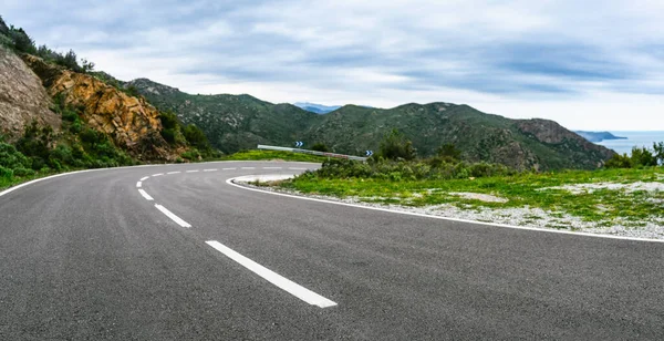 Mediterranean sea coast road into mountains horizon in summer with beautiful bright sun rays - wide angle panorama shot