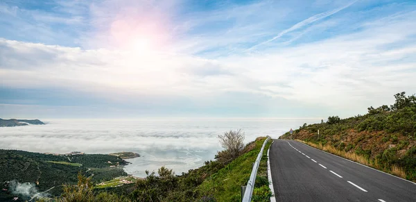 Mediterranean sea coast road into mountains horizon in summer with beautiful bright sun rays - wide angle panorama shot