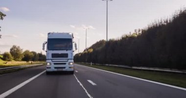 Kargo kamyonu ve kargo karavanı bir otoyolda gidiyor. Beyaz Kamyon sabahın erken saatlerinde mal teslim ediyor. Çok düşük açılı bir araç. Yakın çekim sırasında..