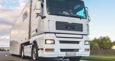 Kargo kamyonu ve kargo karavanı bir otoyolda gidiyor. Beyaz Kamyon sabahın erken saatlerinde mal teslim ediyor. Çok düşük açılı bir araç. Yakın çekim sırasında..