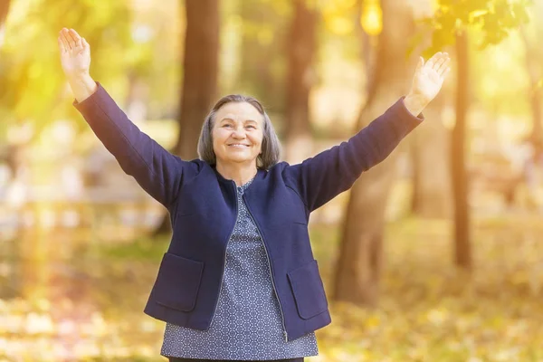 Casual Senior Woman Arms Outstretched Standing Smiling Autumn Park — Stock Photo, Image