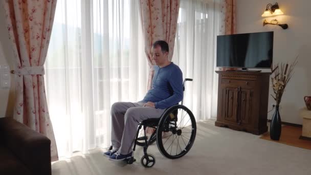悲伤的年轻人坐在轮椅上 从家里或养老院的窗户往外看 慢动作4K 手持式运动 — 图库视频影像
