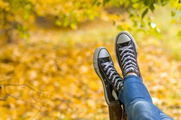 Adolescente chica con zapatillas de deporte está acostado en primer plano del banco —  Fotos de Stock