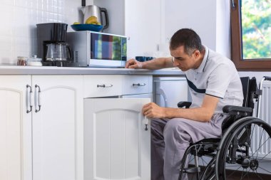 Mutfakta tekerlekli sandalyede oturan engelli genç adam. Yüzüne odaklan..