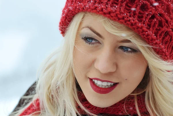 冬帽子手袋とスカーフを身に着けている美しい幸せな笑っている若い女は雪の結晶で覆われています 冬の森の風景の背景 — ストック写真