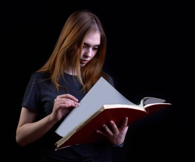 Siyah arka plan üzerine kitap okuyan genç bir kız.