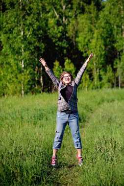 Genç ve güzel Asyalı kız ormanda eğleniyor ve zıplıyor.