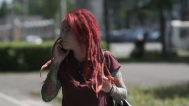  kırmızı saçlı güzel kız ve dreadlocks ve dövme parkta yürüyor