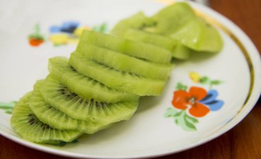 Beyaz tabakta parçalara dilimlenmiş taze kivi