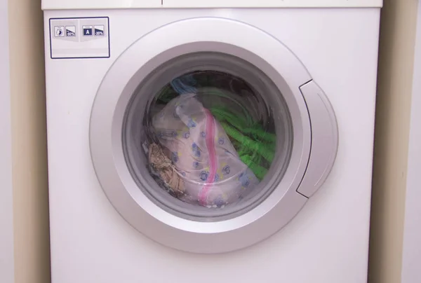 Front view of a washing machine drum during cleaning clothes inside built-in wardrobe