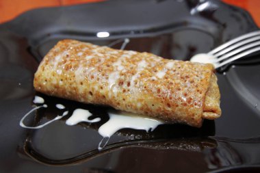 Lezzetli kek meyve siyah tarafından doldurulmuş closeup ve yoğunlaştırılmış süt üzerinde plaka ve nea çatal