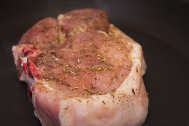 Mutfaktaki tavada kızartılmış baharatlı taze çiğ domuz bifteği.