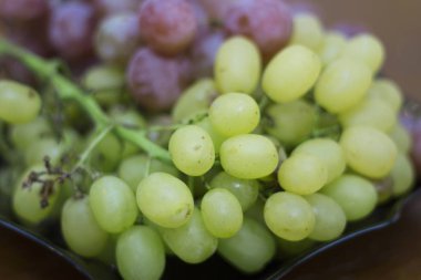 Kırmızı ve beyaz şarap. Siyah tabakta hazır üzüm var.