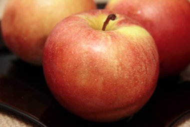 Masanın üzerine siyah plaka üzerinde üç taze kırmızı elma