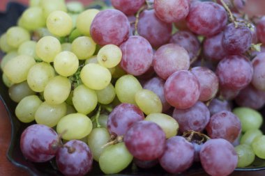 Kırmızı ve beyaz şarap. Siyah tabakta hazır üzüm var.