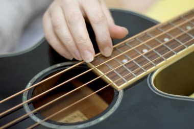 Kadın elinde akustik bir bas gitar ve müzik çalıyor.