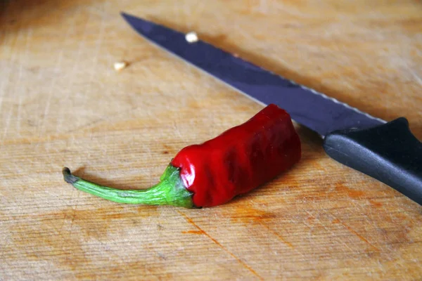 Sharp kniv skära röd peppar på trä matlagning skrivbord — Stockfoto