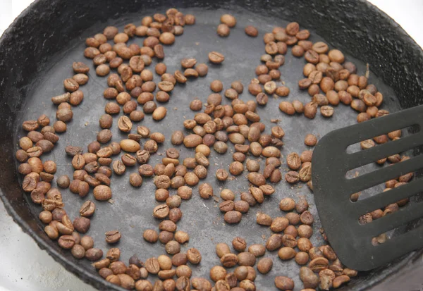 Granos de café verdes tostados en la sartén negra — Foto de Stock