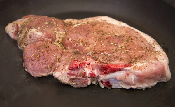 Fresh raw pork steak with spices roasting on frying pan — Stock Photo, Image