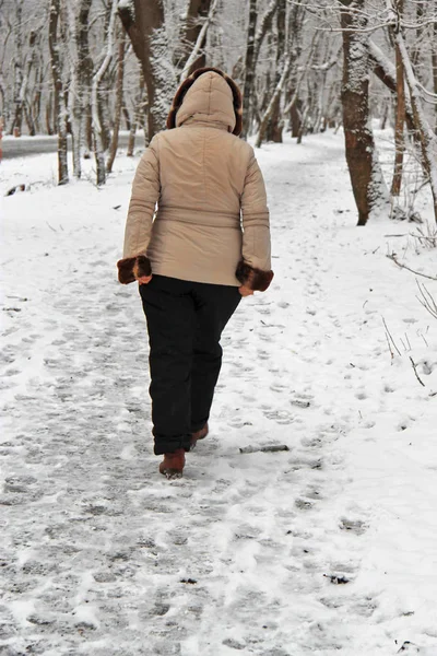 Женщина гуляет одна в зимнем парке на открытом воздухе — стоковое фото