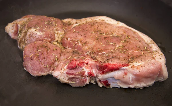Bife de porco cru fresco com especiarias assando na frigideira — Fotografia de Stock
