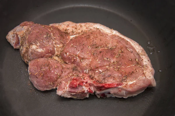 新鮮な生の豚肉ステーキとスパイスがキッチンの黒いフライパンで炒める — ストック写真