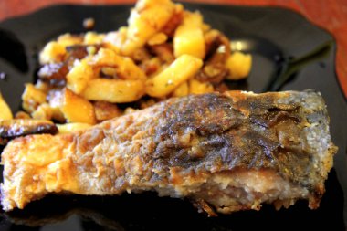 Kızarmış patates ve kızarmış balık ve siyah plaka