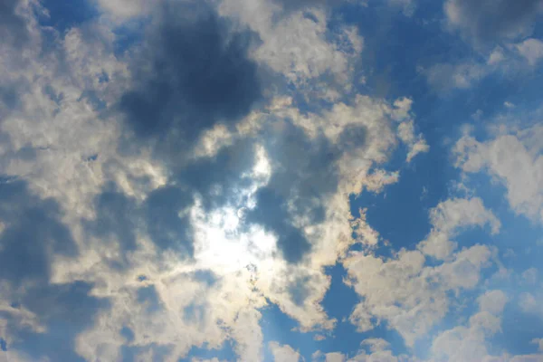 Stormachtige witte wolken op blauwe lucht en zon achter wolken — Stockfoto