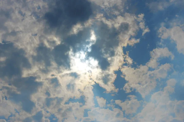 Stormachtige witte wolken op blauwe lucht en zon achter wolken — Stockfoto