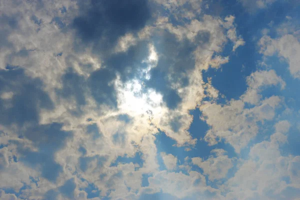 Stormachtige witte wolken op blauwe lucht en zon achter wolken — Stockfoto