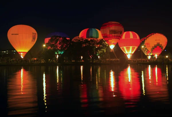 Globos de aire caliente volando en el cielo de la noche cerca del lago — Foto de Stock