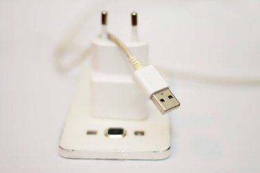 Beyaz telefon ve telefon kablosu beyaz düzlükte izole edilmiş.