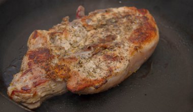 Mutfaktaki kızartma tavasında yarı pişmiş biftek.