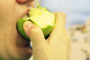 Bir kadın yeşil bir elmayı ısırdı.