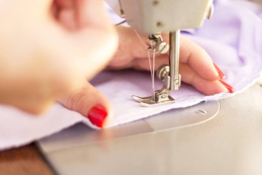 Kadın Taylor dikiş makinesinde çalışıyor. Yakın plan.