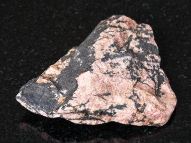 Doğal mineral - ham Rhodonite taş Ural Dağları üzerinden siyah granit üzerine makro çekim
