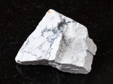 macro shooting of natural rock specimen - white Howlite stone on black granite background clipart
