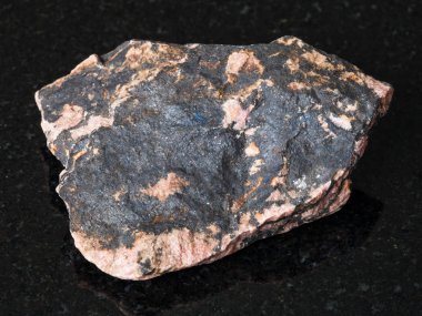 Doğal mineral - kaba Rhodonite gemstone siyah granit Ural Dağları üzerinde makro çekim