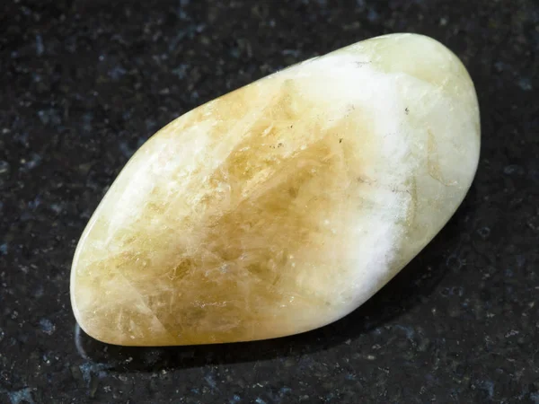 macro shooting of natural rock specimen - tumbled Prasiolite (green quartz , Vermarine) gemstone on black granite background from Brazil