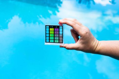 hand holds pH indicator for measure the acidity of water in a swimming pool clipart