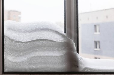 snowdrift between window glasses at home in winter day in Moscow city clipart