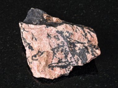 Doğal mineral - kaba Rhodonite taş siyah granit Ural Dağları üzerinde makro çekim
