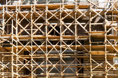 wooden scaffolds on multi-storey building in summer day clipart