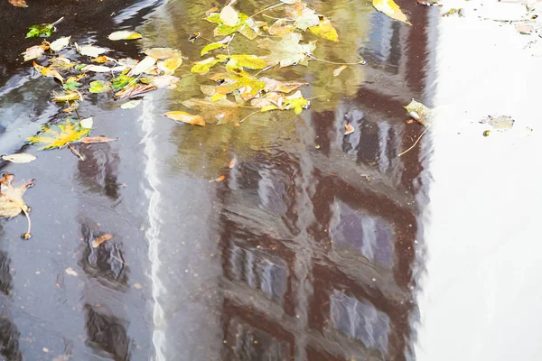 城市道路上的水坑与阳光明媚的秋日公寓房屋的倒影 — 图库照片