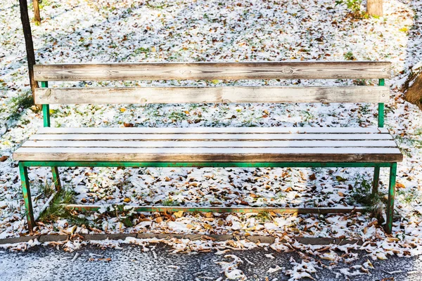 空的长凳覆盖着城市花园的第一雪在寒冷的秋日 — 图库照片