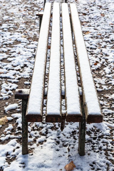 表面的木制长凳覆盖着第一个雪在城市公园在寒冷的秋日 — 图库照片