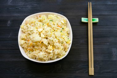 Çin mutfağı yemek - Fried Rice karides, sebze ve yumurta (Yangzhou pirinç) ile sunulan kısmı yemek çubukları ile üstten görünüm koyu ahşap tablo