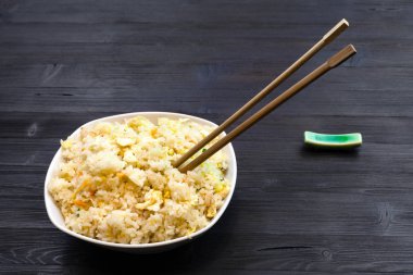 Çin mutfağı yemek - Fried Rice karides, sebze ve yumurta (Yangzhou pirinç) kısmı koyu ahşap masa üzerinde yemek çubukları ile