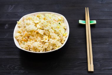 Fried Rice karides, sebze ve yumurta (Yangzhou pirinç) kısmını koyu ahşap masa üzerinde yemek çubukları ile Çin mutfağı çanak-